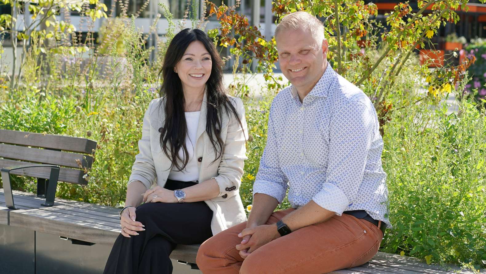 Två personer sitter på en bänk och ler.